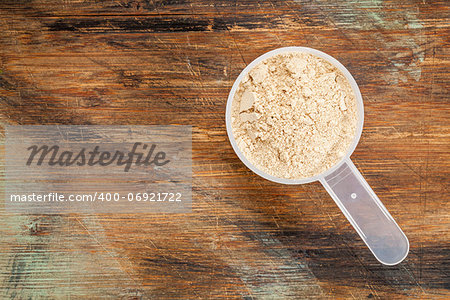 measuring scoop of maca root  powder - top view against painted wood background