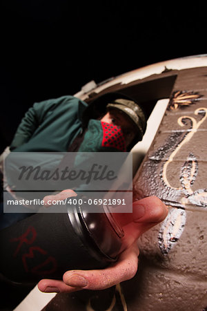 Man hiding behind face mask with spray paint can