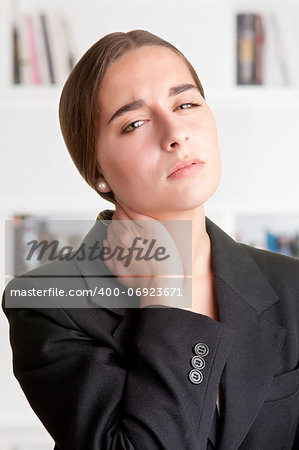 Young businesswoman with neck pain with a bookshelf behind her