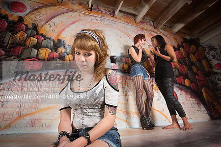 Shy teenager looking over at two girls talking about her