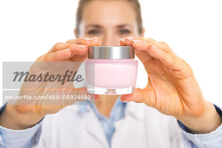 Closeup on cream bottle in hand of cosmetologist