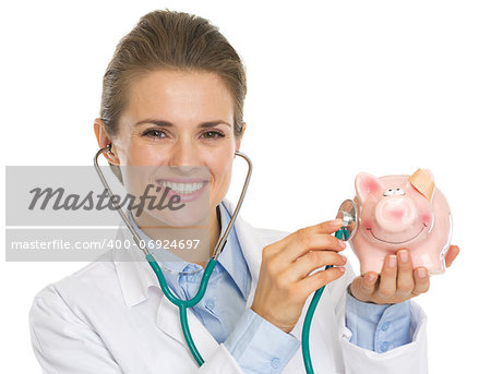 Smiling doctor woman listening piggy bank with stethoscope