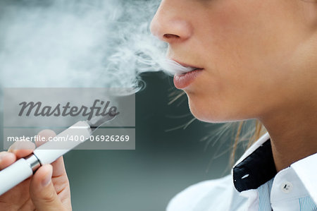 closeup of woman smoking e-cigarette and enjoying smoke. Copy space