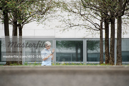 young businesswoman smoking cigarette during break out of office building. Wide shot, copy space
