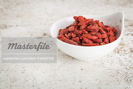 small ceramic bowl of  dried goji berries against a ceramic tile background with a copy space