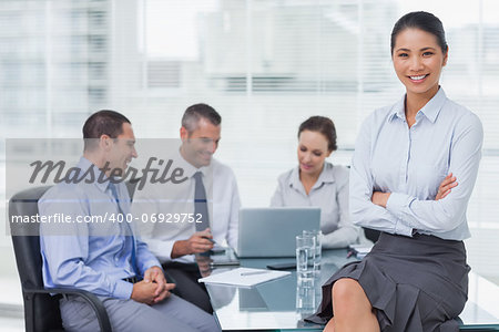 Smiling businesswoman in bright office posing while workmates talking together