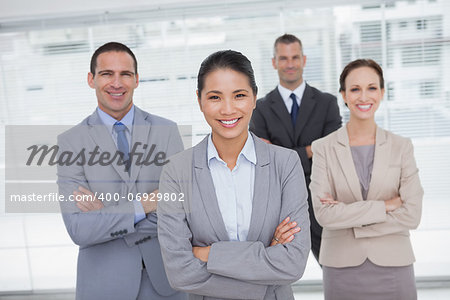 Cheerful work team posing crossing arms in bright office