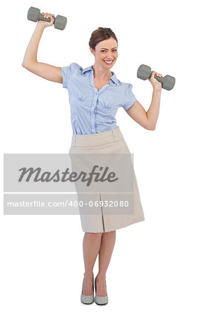 Strong businesswoman lifting dumbbells looking at camera against white background