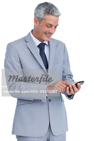 Cheerful businessman sending text message against white background