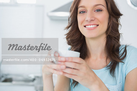 Radiant brunette drinking coffee in her kitchen