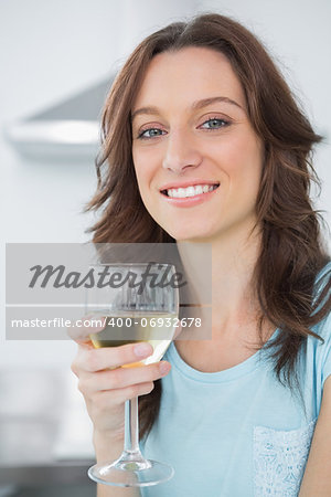 Brunette in her kitchen having a glass of white wine