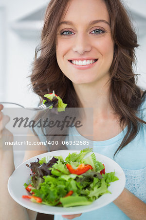 Brunette having salad in her kitchen