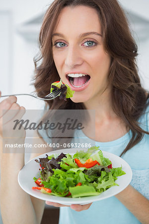 Healthy brunette having salad in her kitchen