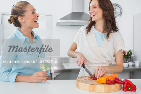 Brunette cooking while talking to her friend in her kitchen