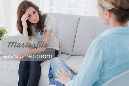 Upset woman sitting on the couch and looking at therapist in a private session