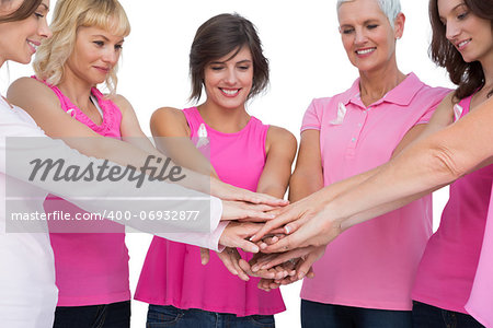 Cheerful women posing in circle holding hands wearing pink for breast cancer on white background