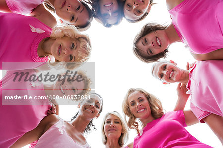 Cheerful women smiling in circle wearing pink for breast cancer on white background