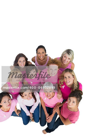 Cheerful pretty women looking up wearing pink for breast cancer on white background