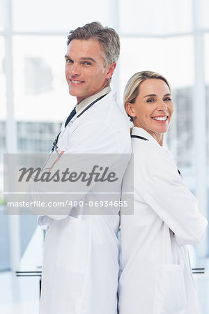 Experienced doctors posing together back to back in medical office