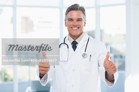 Experienced doctor posing thumbs up in medical office