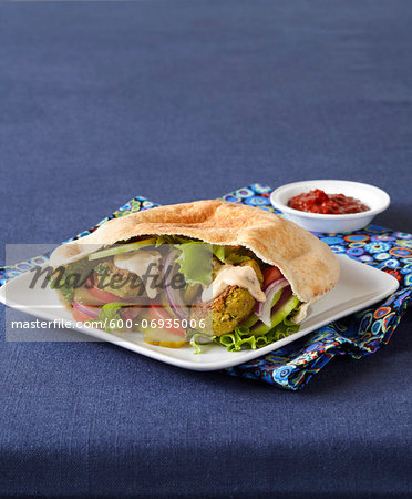 Falafel Sandwich in Pita with Tahini Sauce, Blue Background, Studio Shot Falafel Sandwich in Pita with Tahini Sauce, Blue Background, Studio Shot