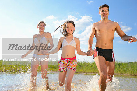 Happy Family Running in Shallow Water of Lake in Summer, Bavaria, Germany