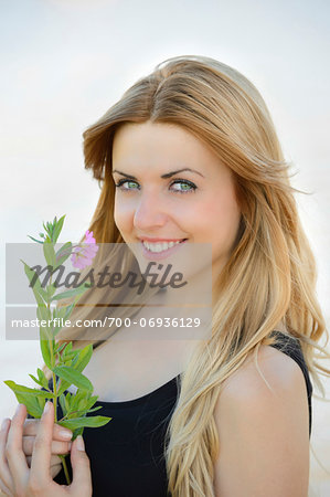 Portrait of a young woman with a flower outdoors in summer, Germany