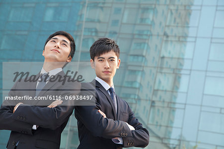 Two young businessmen outside glass building, portrait