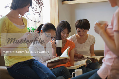 Five friends sitting in coffee shop, reading