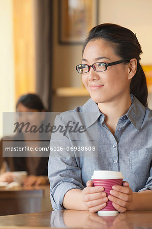 Young woman at coffee shop looking away in contemplation