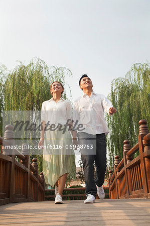 Young Couple Holding Hands and Crossing a Bridge