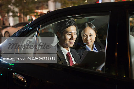 Two Business People Working In Car Back