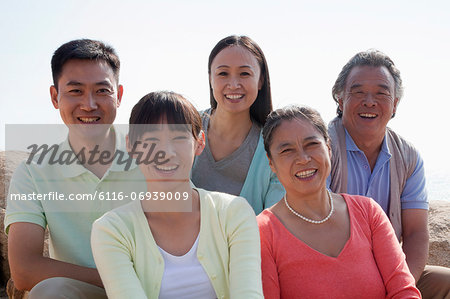 Portrait of smiling multigenerational family sitting on the rocks outdoors, China