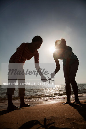 Silhouette of mother and daughter holding a starfish on the beach