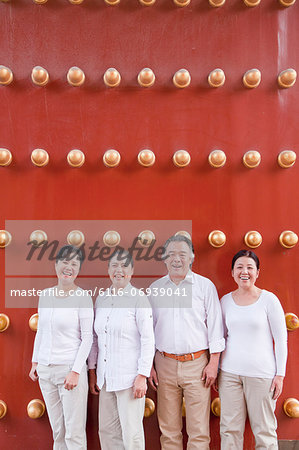 Group of mature people standing next to traditional Chinese door, portrait
