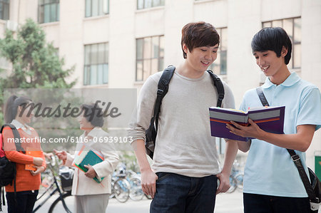 Students discussing and looking at the book, another student talking with professor on the background