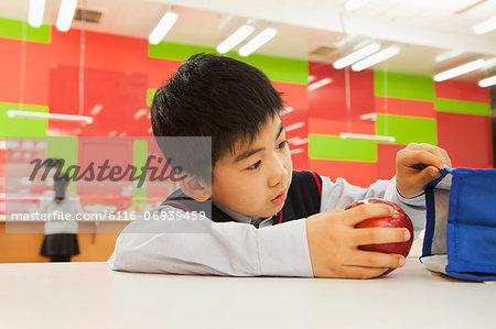 School boy checking lunch bag in school cafeteria