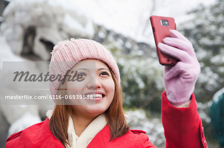 Young woman taking picture with cell phone in snow