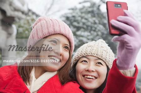 Two friends taking picture with cell phone in snow