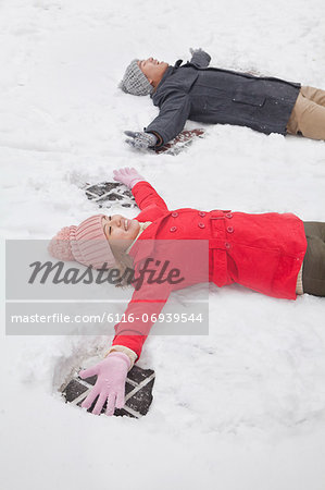 Young couple laying in snow making snow angels