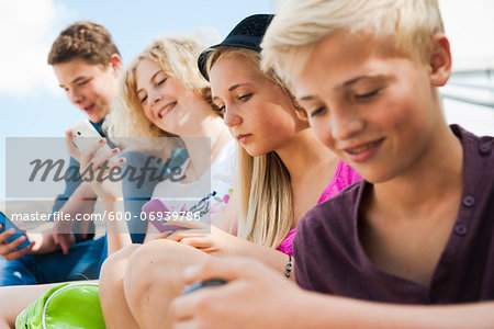 Teenagers using Cell Phones Outdoors, Mannheim, Baden-Wurttemberg, Germany