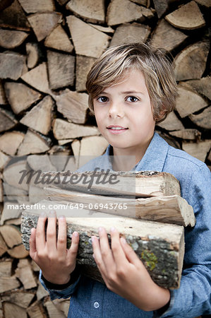 Boy carrying firewood outdoors