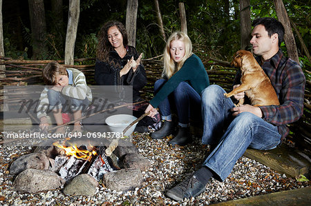 Family relaxing by fire outdoors