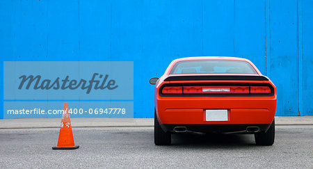 Supercharged Muscle Car parked next to Blue Wall