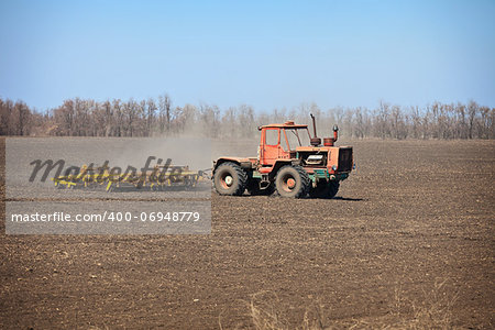 Old agricultural tractor sows in a field