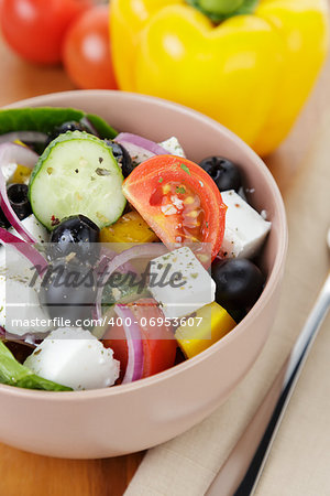 fresh greek salad in clay bowl, on wood table