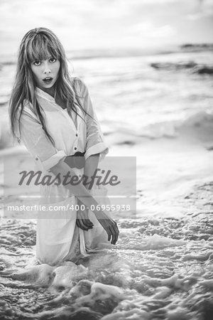 Beautiful model in shirt dress standing in the sea in black and white artistic shot