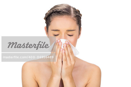 Sick young model on white background blowing her nose