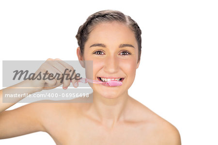 Smiling young model on white background brushing her teeth