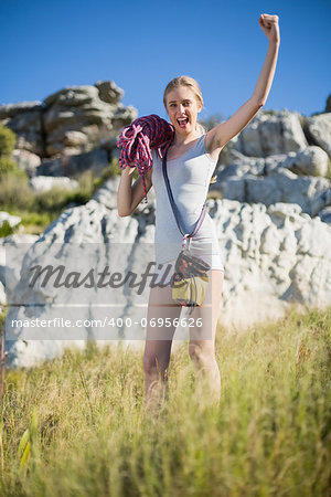 Woman holding climbing equipment and showing muscle looking at camera